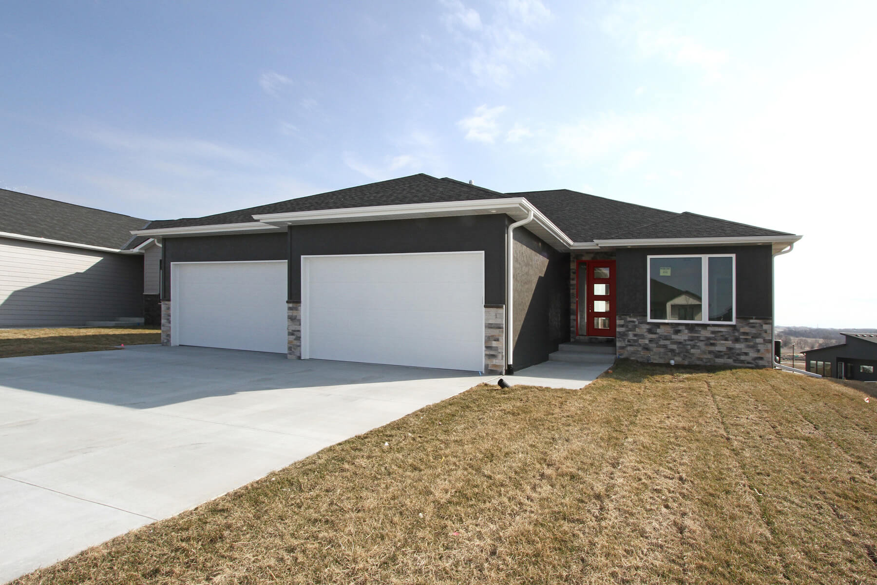 Wide cinematic establishing shot of a newly-built luxury contemporary home in Lincoln Nebraska at golden hour, warm suns